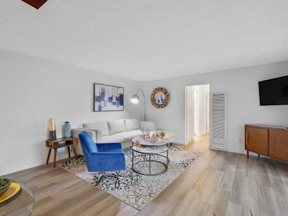 A living room with a blue chair and a white couch at Verandas Apartments, California, 91791