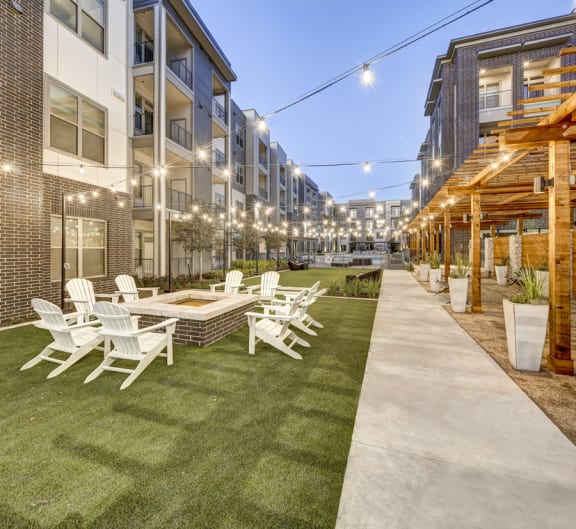 a patio area with white chairs and tables and buildings at Arise Riverside, Austin, 78741