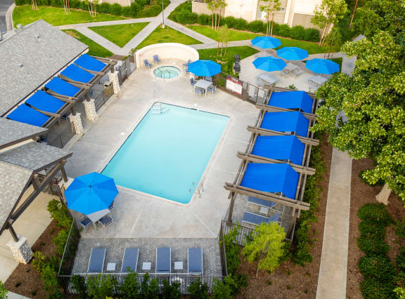a resort style pool with blue umbrellas and chairs around it at Sunstone Place, Riverside, CA, 92505