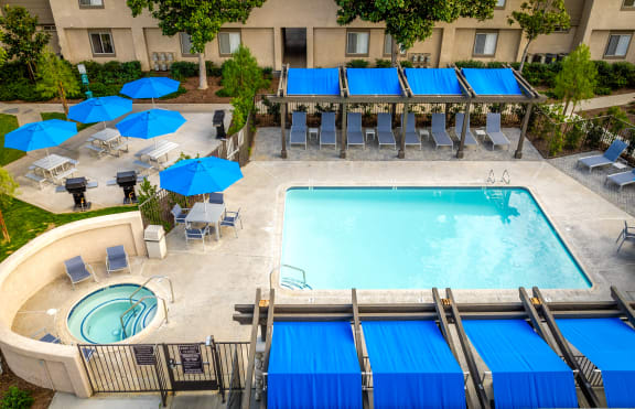 a swimming pool with blue umbrellas and chairs near a hotel pool at Sunstone Place, California, 92505