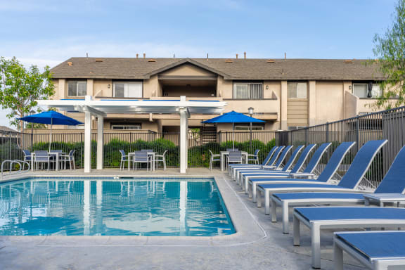 a resort style pool with chairs and umbrellas at the resort at governors crossing at Sunstone Place, Riverside, CA