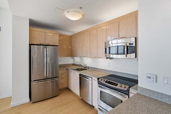 A kitchen with a refrigerator, oven, and microwave at The Grand Apartments, Oakland