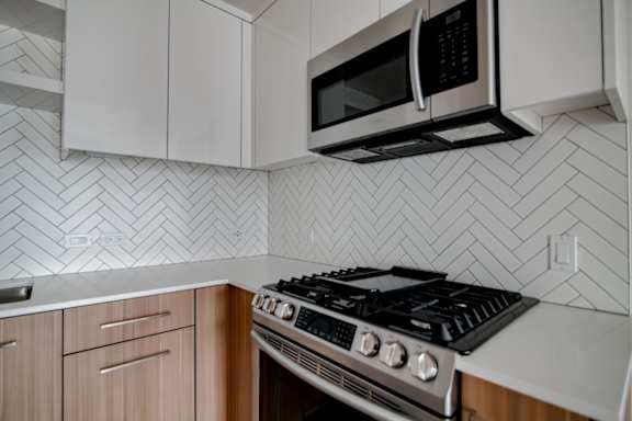 A modern kitchen with a stove, microwave, and cabinets.
