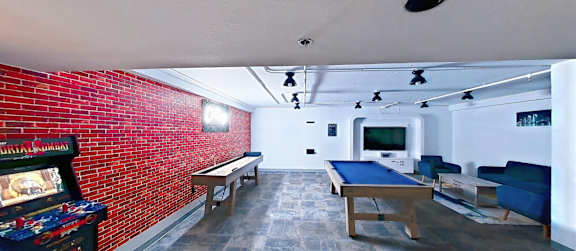 A room with a pool table and a red brick wall.