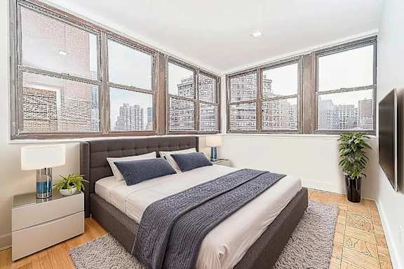 A bedroom with a large bed and a window overlooking a cityscape.