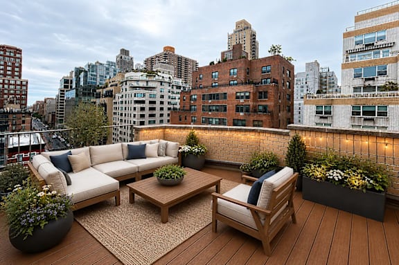 A wooden deck with a couch, chairs, and potted plants.