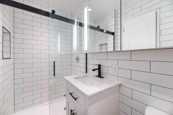 A white bathroom with a black and white tile wall.