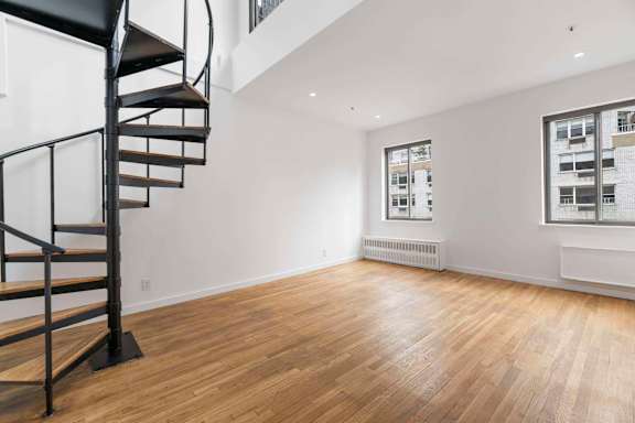 A room with a spiral staircase and wooden flooring.