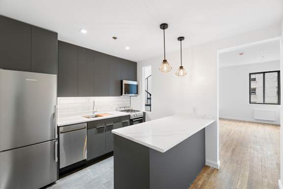 A modern kitchen with a refrigerator, sink, and cabinets.