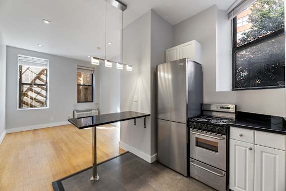 A kitchen with white cabinets and black countertops.