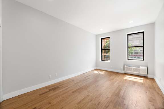 A room with wooden floors and two windows.
