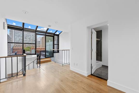 A room with a white wall and a door leading to a balcony.