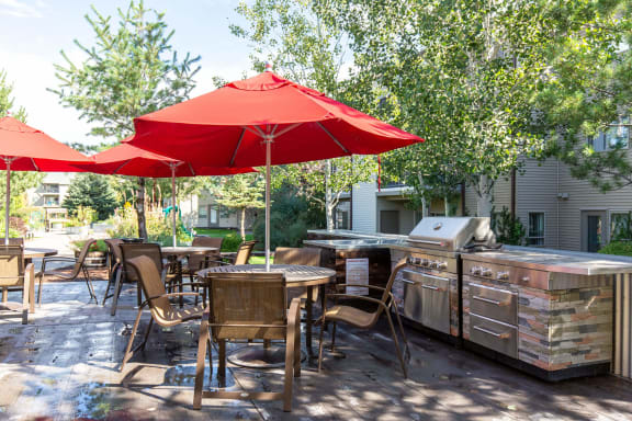 an outdoor patio with a barbecue grill and tables with umbrellas at Mullan Reserve Apartments, Missoula, MT 59808