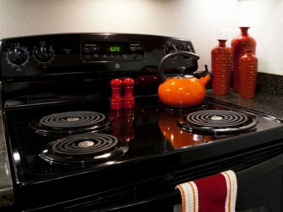 a black stove top oven sitting next to a orange teapot at Mullan Reserve Apartments, Missoula, 59808