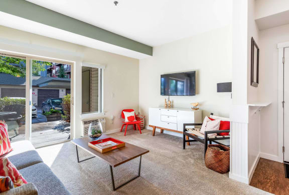 a living room with white walls and a sliding glass door that leads to a patio at Mullan Reserve Apartments, Missoula, MT