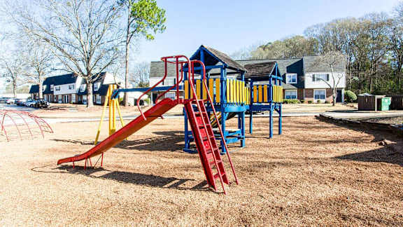 A playground with a red slide and a blue and yellow structure.