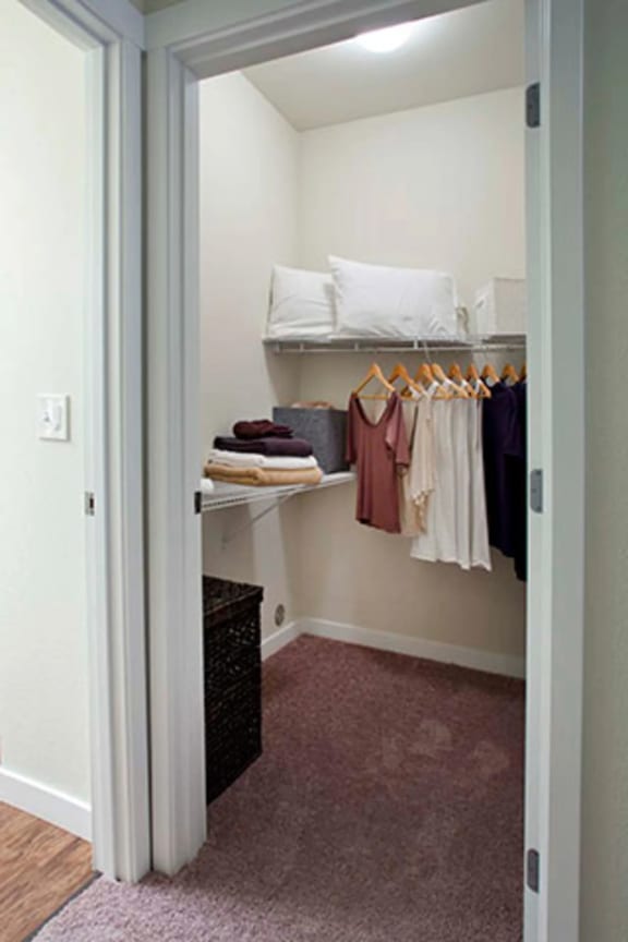 a small walk in closet with shelves and a basket