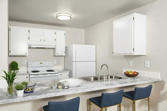 A kitchen with a white refrigerator, a white oven, and a white countertop with a bowl of fruit on it. at Ironwood Apartments, Coeur dAlene, ID, 83814