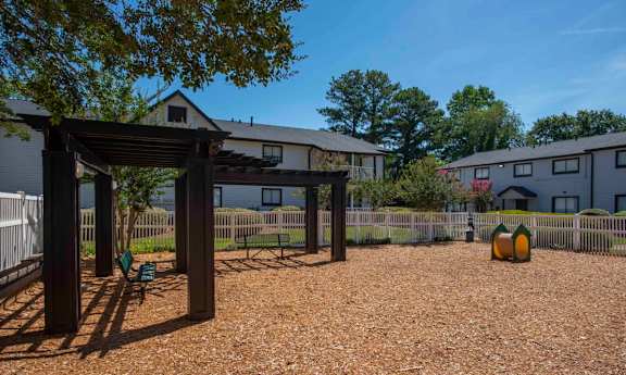 A gravel area with a wooden structure and a fence in the background.