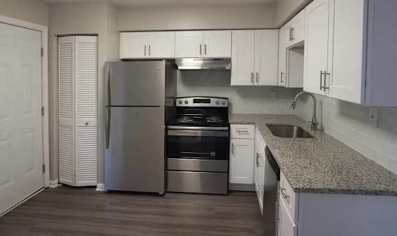 A kitchen with a refrigerator, oven, and sink.