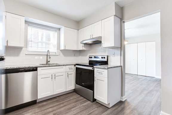A kitchen with white cabinets and a black countertop.