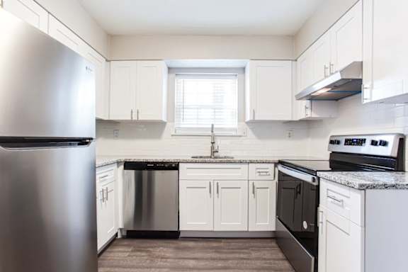 A kitchen with white cabinets and a stainless steel refrigerator.