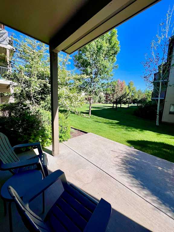 A patio with a table and chairs overlooks a green lawn. at Mullan Reserve Apartments, Missoula, Montana