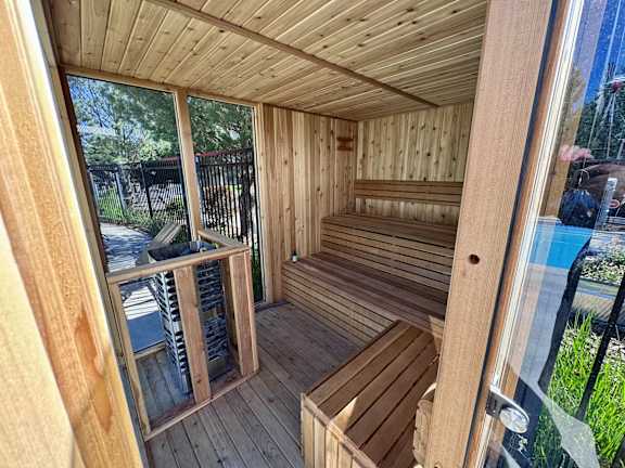 A wooden sauna with a glass door and a bench inside.