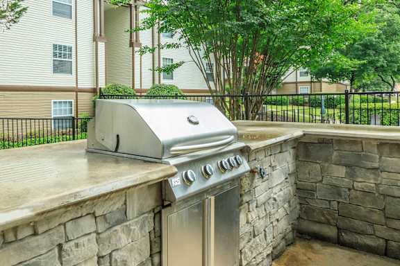 A stainless steel grill is on a stone patio.