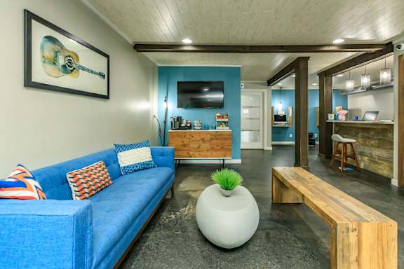 A blue couch with a white vase on the floor.