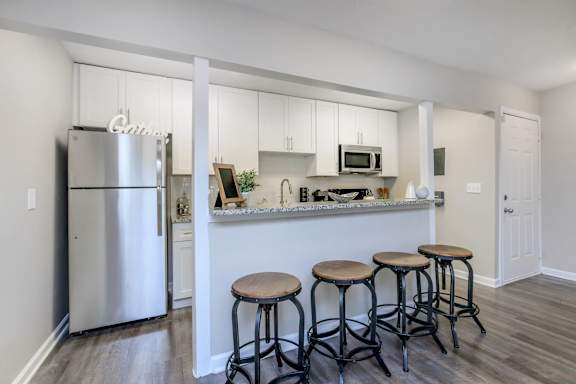 A kitchen with white cabinets and a stainless steel refrigerator.