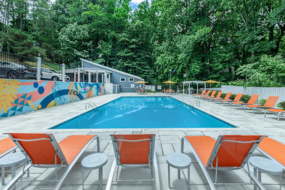 A pool surrounded by orange chairs and a mural at Crest at East Cobb Apartments, Georgia, 30062