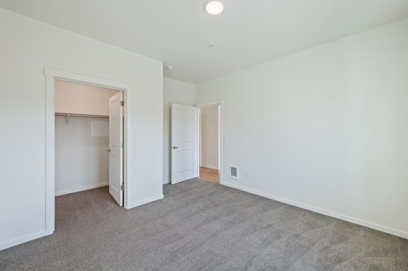 a bedroom with white walls and carpet and a door to a closet at Gateway Apartments, East Wenatchee , WA 98802