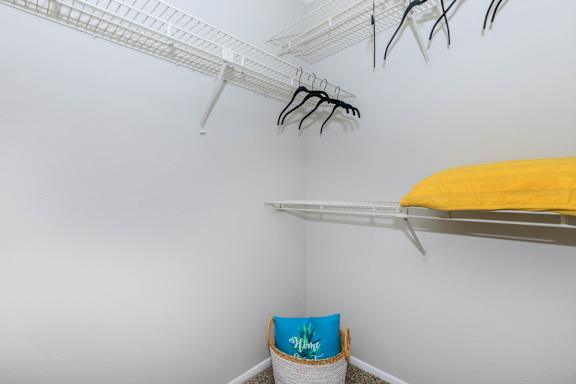 a closet with shelves and a yellow bed in it and a white wall with shelves