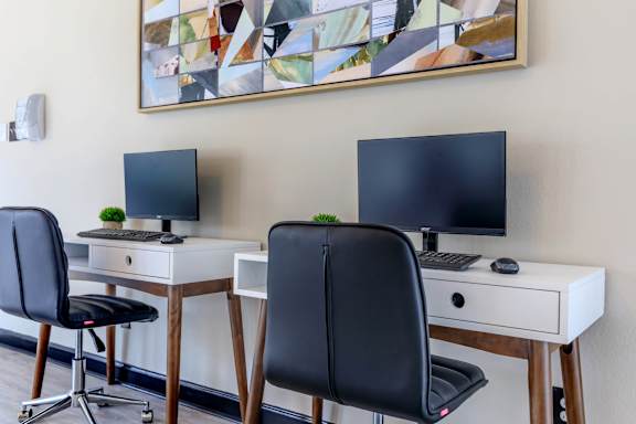 two desks with two monitors and two chairs in a room