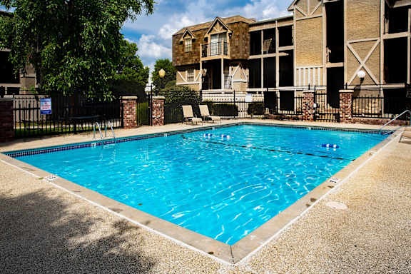 A swimming pool in front of a building with a fence around it.