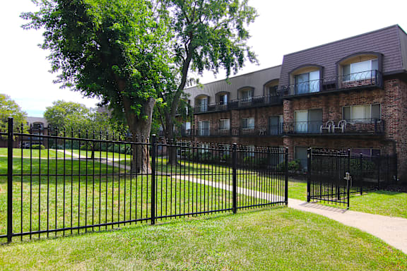 A black iron fence surrounds a green lawn.