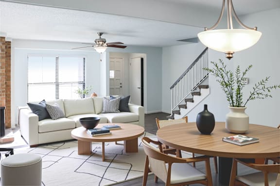 A living room with a white couch, a wooden table, and a ceiling fan.