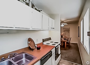 a kitchen and living room with a dining room in the background