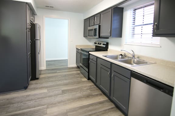 A kitchen with black cabinets and a stainless steel refrigerator.