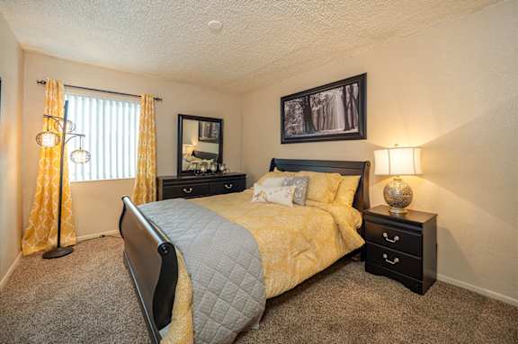 A bedroom with a bed, nightstand, and lamp.