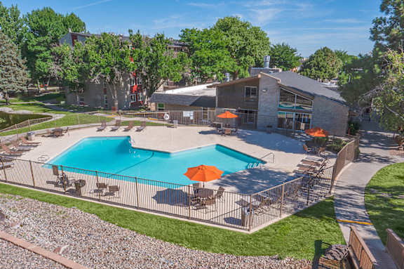 A swimming pool surrounded by a fence and chairs.