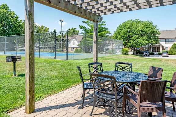 A patio with a table and chairs under a wooden pergola.