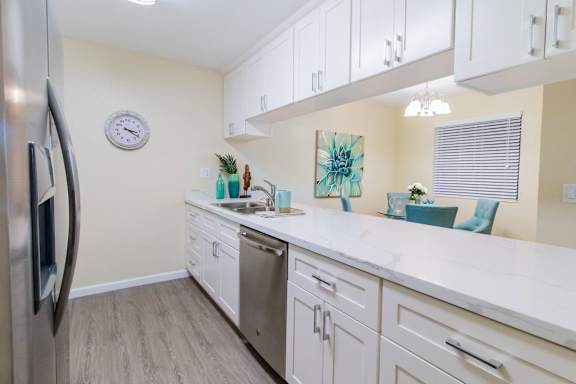 A kitchen with white cabinets and a marble countertop.