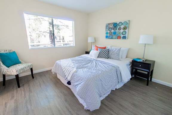 A bedroom with a bed, chair, and lamp.