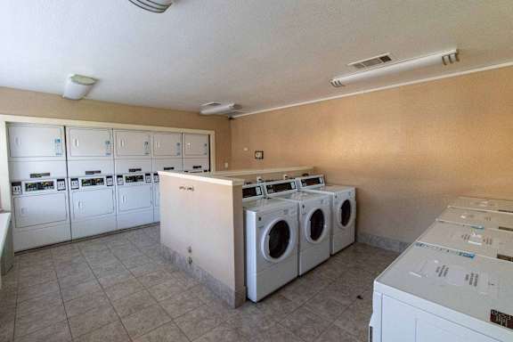 A laundry room with a row of washing machines.