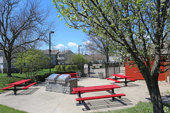 A park with picnic tables and a red building.