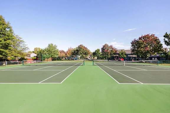 A tennis court surrounded by trees and buildings.