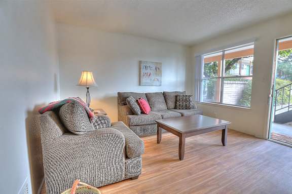 A living room with a grey couch, a brown coffee table, and a lamp.