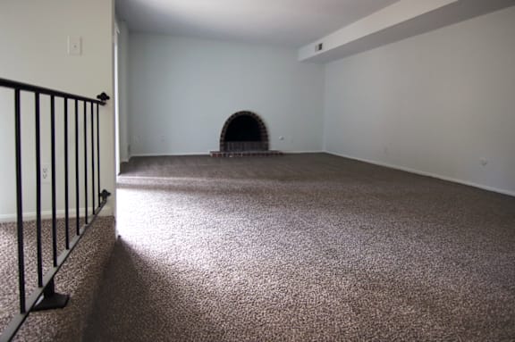 A room with a carpeted floor and a fireplace.